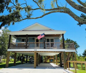 A two-story house with a balcony, an American flag, and the number 116 on the front.