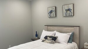 A bedroom with a bed, a ceiling fan, two wall art pieces, and a bedside table with a lamp. - Coastal home walking distance to the beach (Long Beach)
