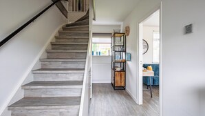 A staircase with wooden steps and a black handrail, leading to a room with a blue sofa and a wooden side table.