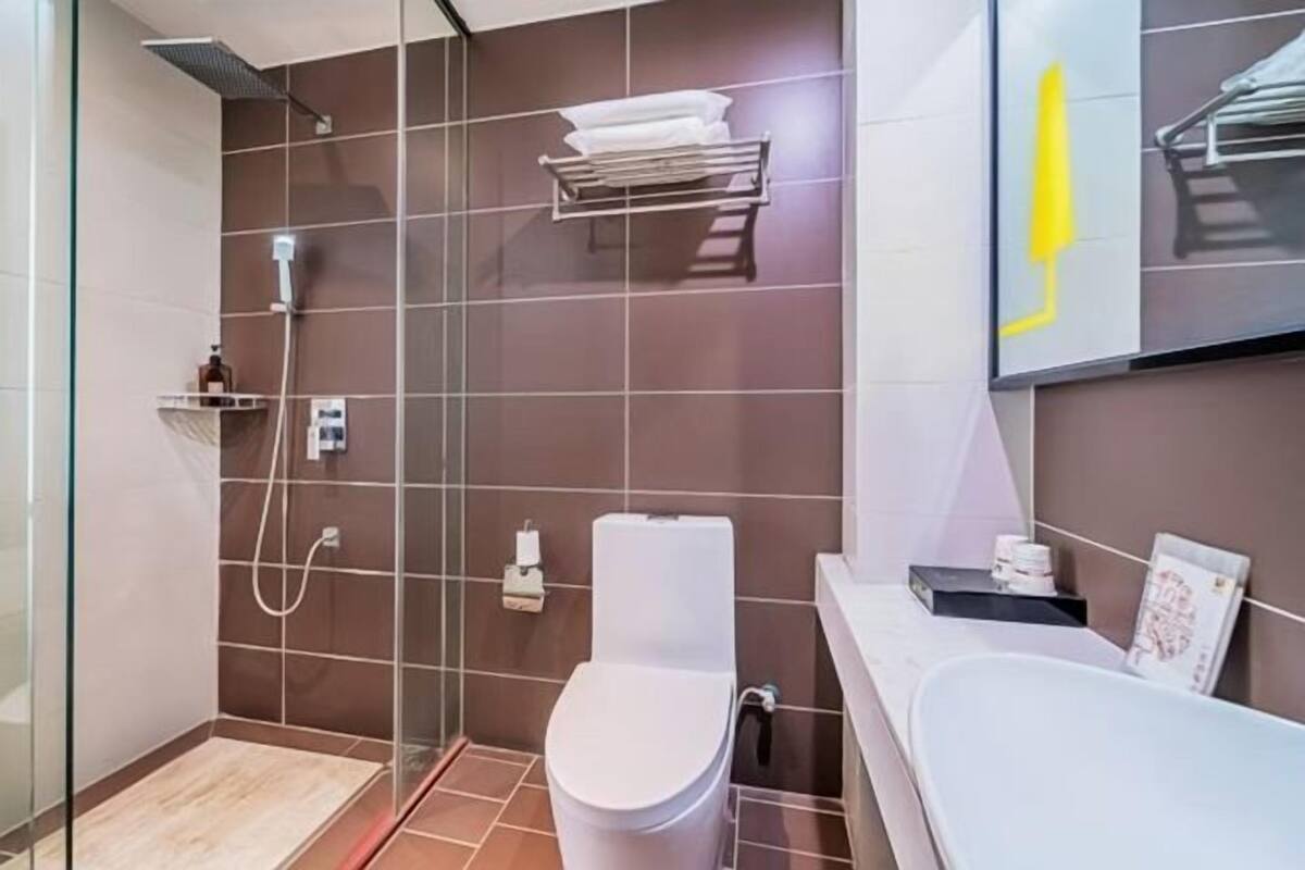 A modern bathroom with a glass-enclosed shower, a white toilet, a bathtub, and a towel rack on the wall.