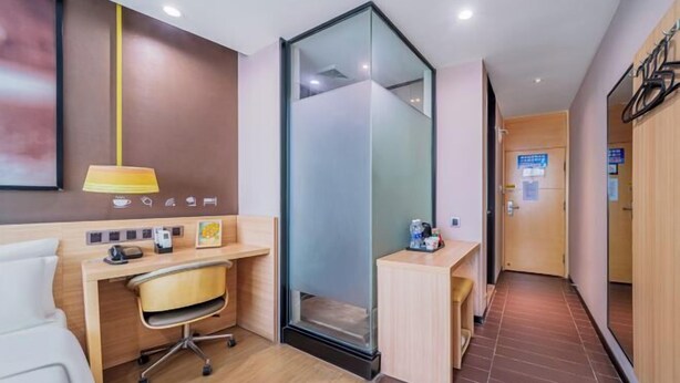 Camera d'albergo con scrivania, sedia e divisorio in vetro.