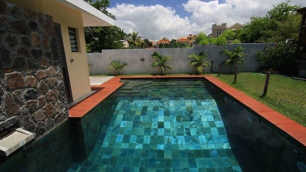 Una piscina con un muro de piedra en un lado y un borde rojo.