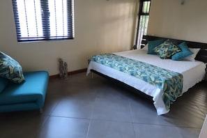 Une chambre à coucher avec un lit, un canapé bleu et une fenêtre avec des stores.