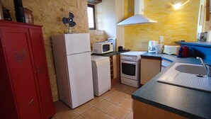 A compact kitchen with a red cabinet, a white refrigerator, a microwave, an oven, and a sink.