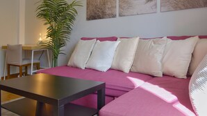 Uma sala de estar com sofá, mesa de centro, planta e obras de arte na parede.