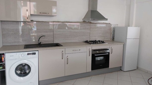 A compact kitchen with a washing machine, a stove, a sink, and a refrigerator. - APPT T2 Cirique (Anses d'Arlet)