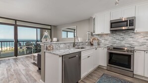 A modern kitchen with a large island, stainless steel appliances, and a view of the ocean. - Direct oceanfront rennovated condo with panoramic views of ocean and bay right on the beach! (Ocean City)