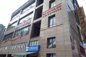 Um edifício com vários andares e letreiros comerciais, incluindo uma placa azul para uma loja de roupas femininas e letreiros vermelhos para um negócio.