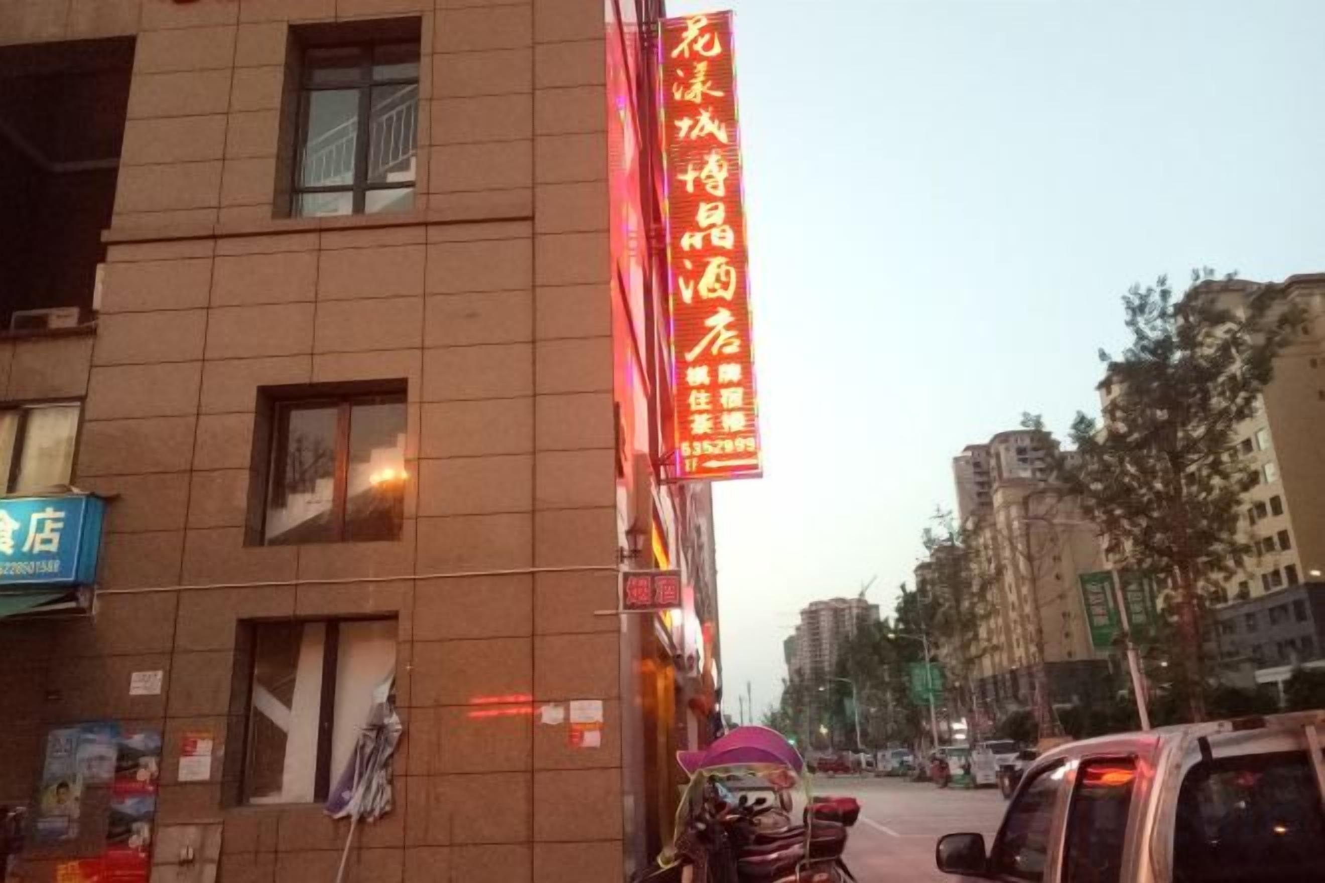 A building with a prominent red sign, a storefront with a blue sign, and a parked motorcycle.