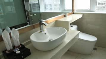 Un baño moderno con un lavamanos blanco, un inodoro y un ventanal que proporciona luz natural.