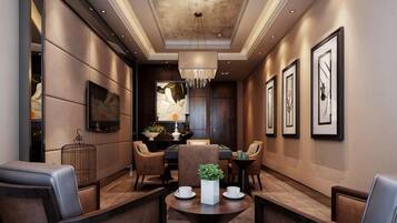 A modern hotel lobby with a dining area, framed artwork on the walls, and a chandelier.