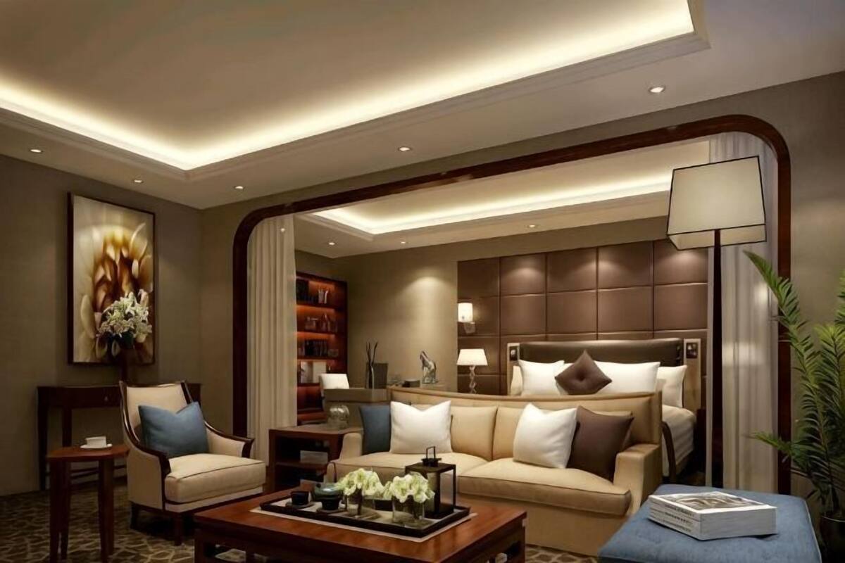 A modern hotel room with a sofa, a coffee table, a bookshelf, and a large bed.