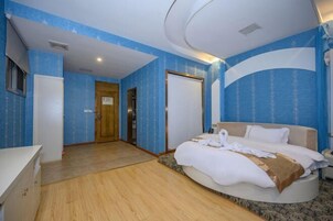 Quarto de hotel com uma cama, uma mesa e uma porta que dá para outro cômodo.