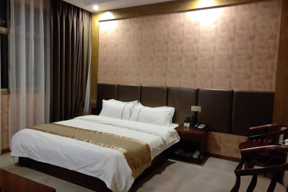 A hotel room with a bed, a nightstand, a chair, and a wall with a textured pattern.