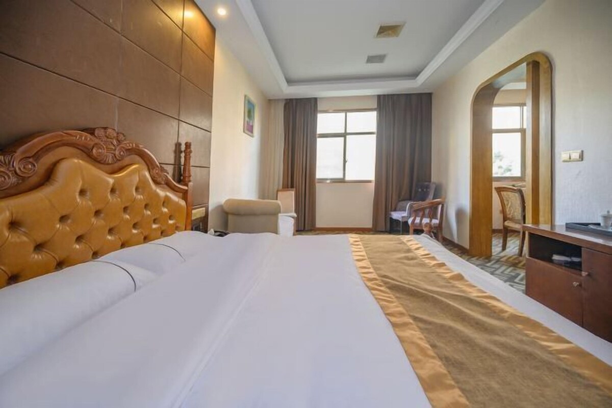 Habitación de hotel con una cama grande, un escritorio, una silla y un espejo.