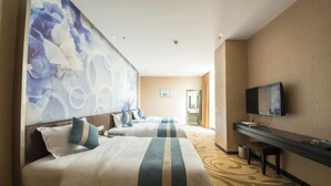 Habitación de hotel con dos camas, un televisor, un escritorio y un gran mural floral en la pared.