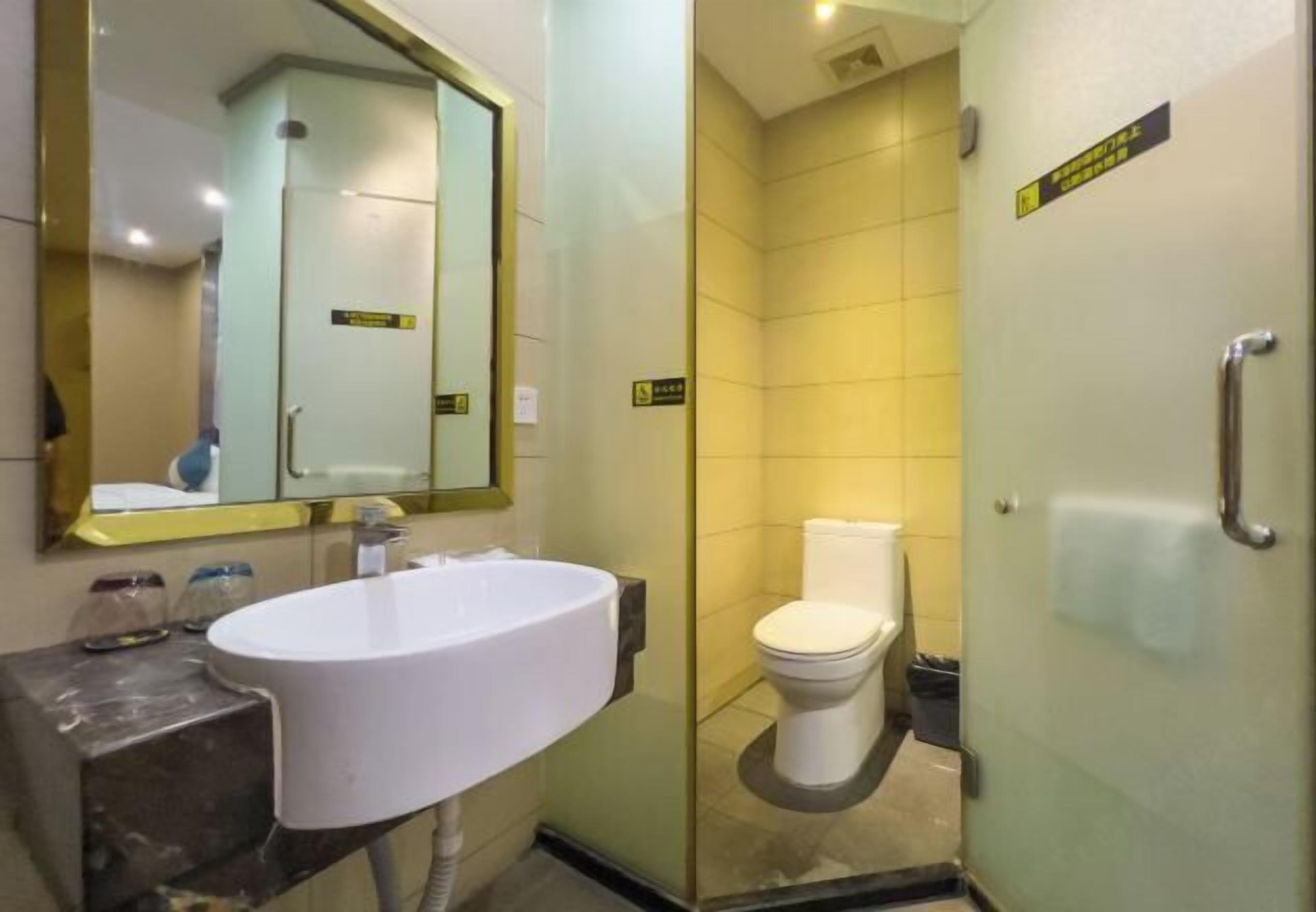 A bathroom with a white sink, a toilet, and a glass shower enclosure.