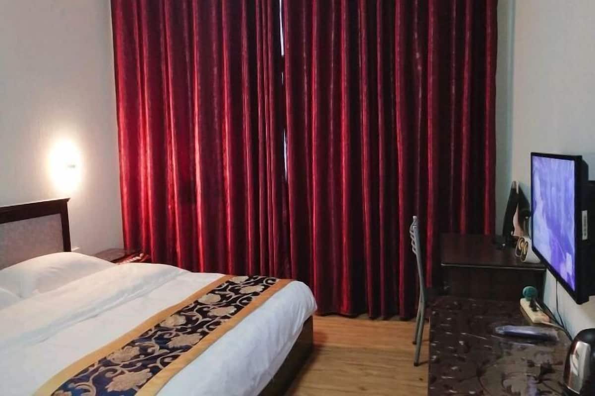 Ein Hotelzimmer mit einem Bett, einem Fernseher und einem roten Vorhang.