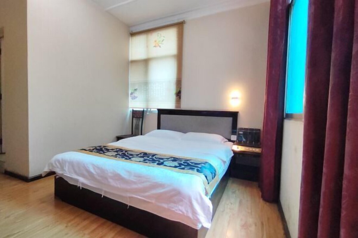 Quarto com cama, mesa de cabeceira e janela com cortinas.