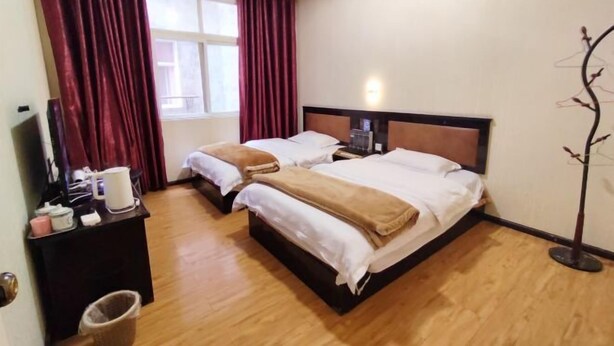 A hotel room with two beds, a desk with a chair, a TV, and a window with curtains. - Yuxi Jinhua Hotel (Yuxi)