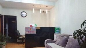 A reception area with a reception desk, a couch, a clock, and a potted plant. - Yuxi Jinhua Hotel (Yuxi)