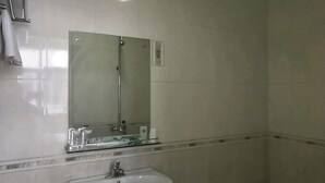 A bathroom with a sink, mirror, and shower. - Yuxi Jinhua Hotel (Yuxi)