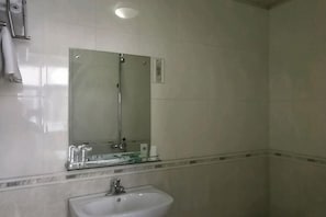 A bathroom with a sink, mirror, and shower.