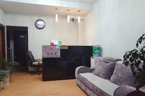 A reception area with a reception desk, a sofa, a clock, and a potted plant. - Yuxi Jinhua Hotel (Yuxi)