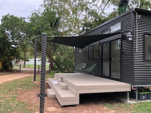 Una casa moderna con una terraza, mobiliario exterior y un amplio ventanal.