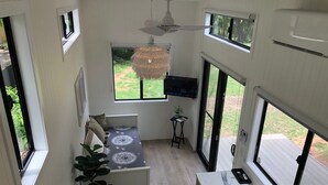A compact kitchen with a central island, a ceiling fan, and large windows offering a view of the outdoors.