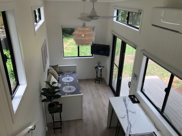 Una cocina compacta con una isla central, ventilador de techo y ventanas amplias con vistas al exterior.