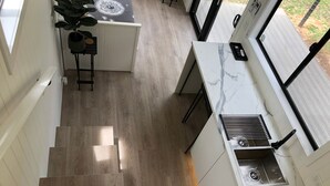A modern kitchen with a marble countertop, a sink, and a staircase leading to another level.