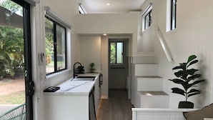 A compact kitchen with a window, a sink, and a staircase leading to a loft area.