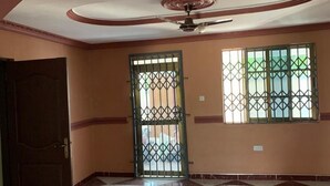 A spacious room with a high ceiling, a ceiling fan, and two windows with metal bars. - SWATSON HOTEL (Kumasi)