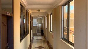 A hotel corridor with a check-in counter at the end, a fire extinguisher on the wall, and a sign indicating room 01. - SWATSON HOTEL (Kumasi)