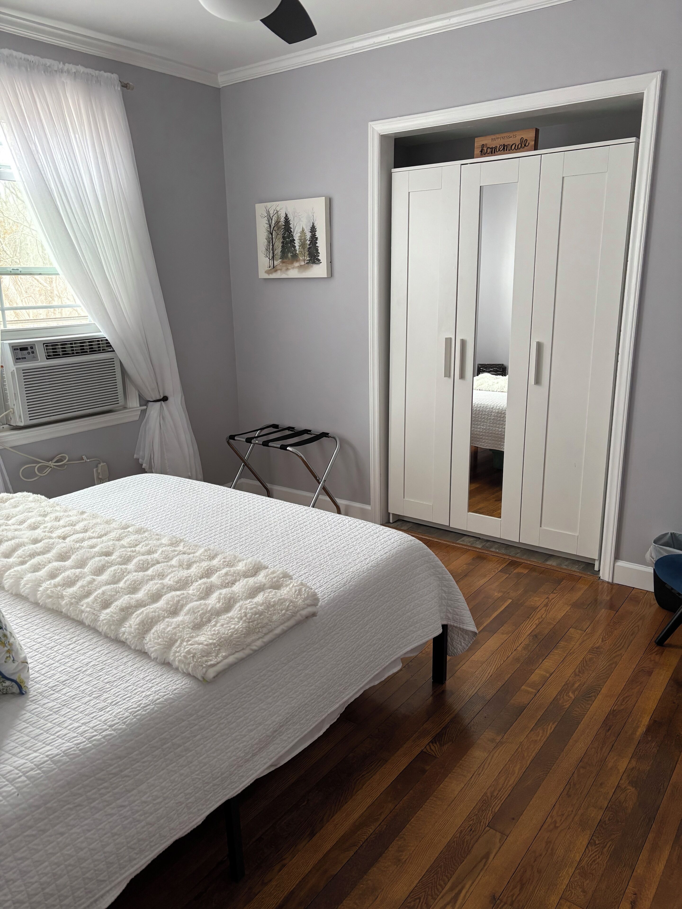 Une chambre à coucher avec un lit, une armoire, un radiateur et une fenêtre avec des rideaux.