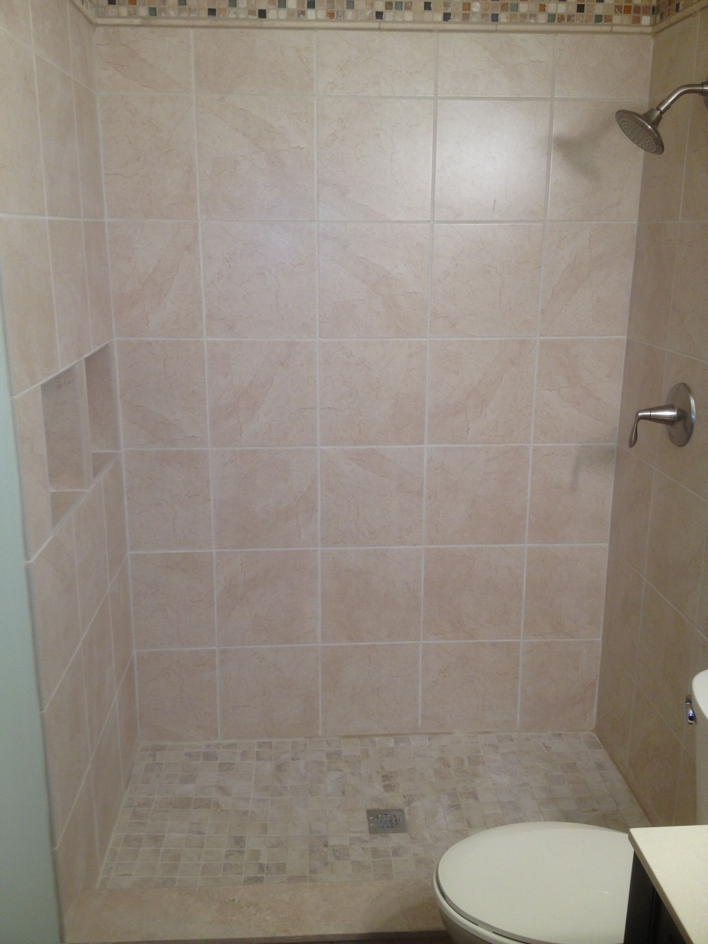 A bathroom with a shower, toilet, and tiled walls.