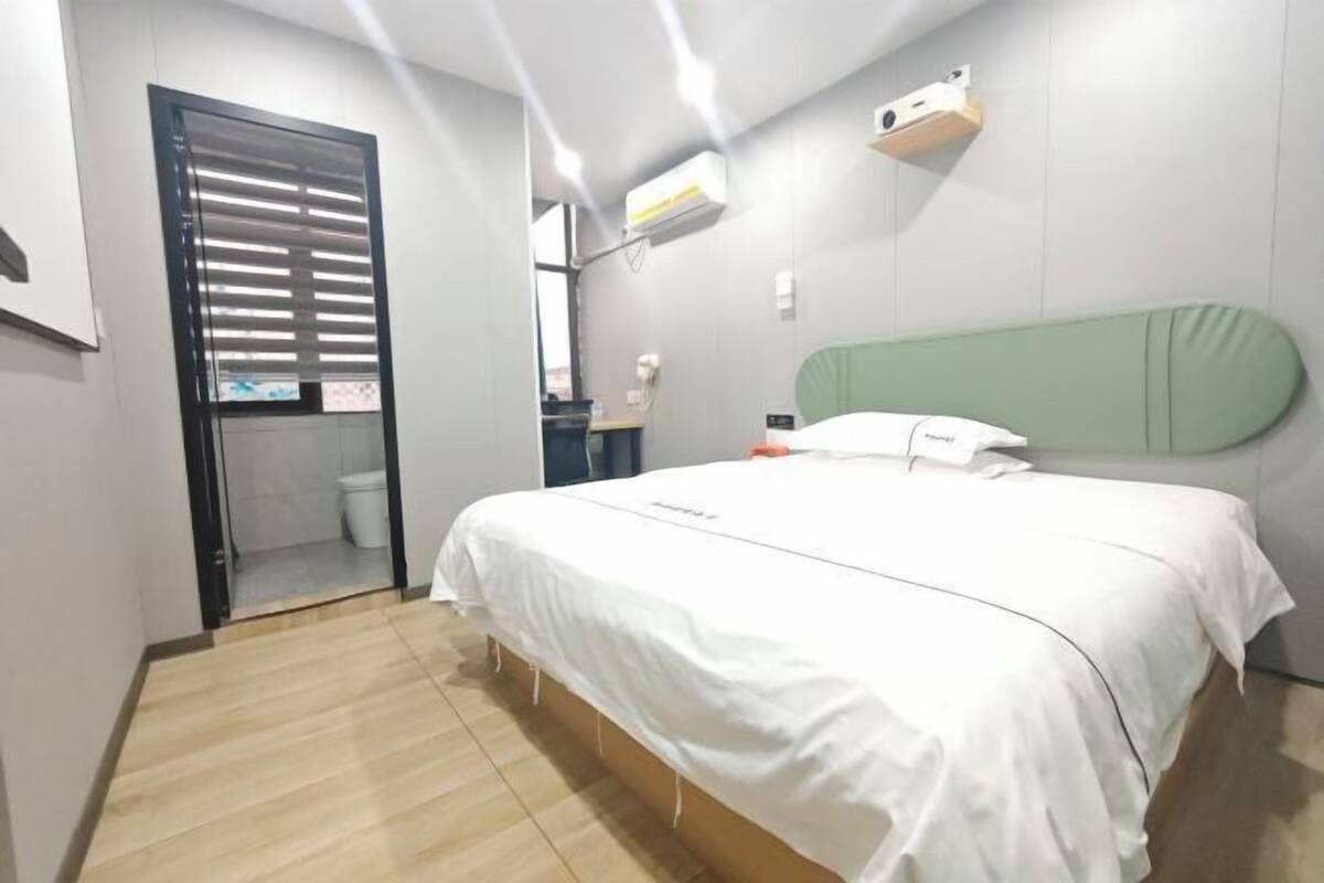 A hotel room with a bed, a wardrobe, a mirror, and a small desk.