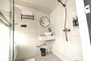 Een badkamer met wastafel, spiegel, handdoekrek en douche.