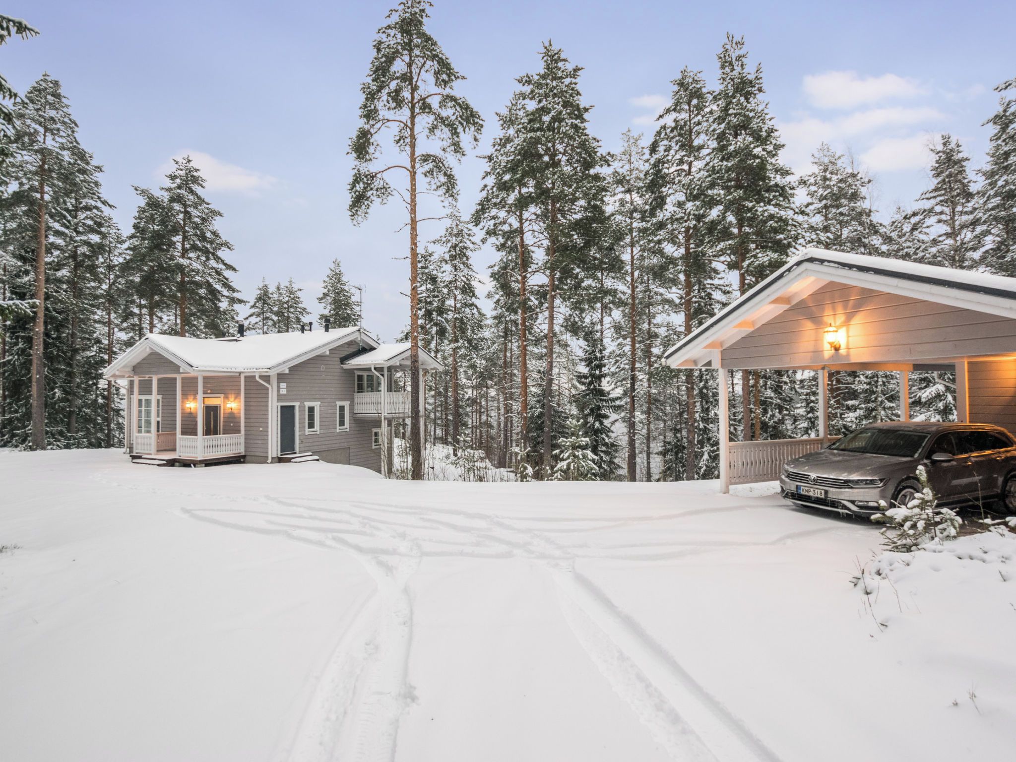 A two-story cabin with a covered porch and a car parked in front.