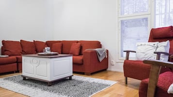 A living room with a red sofa set, a white sideboard, and a patterned rug.