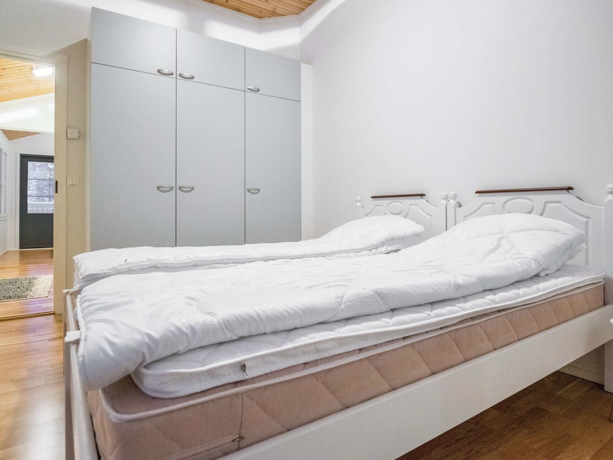 Une chambre à coucher comprenant un lit, une armoire et une porte donnant sur une autre pièce.