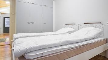 Une chambre à coucher comprenant un lit, une armoire et une porte donnant sur une autre pièce.