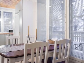 Ein Essbereich mit Tisch und Stühlen, einer Kerze und einem Fenster mit Jalousien.