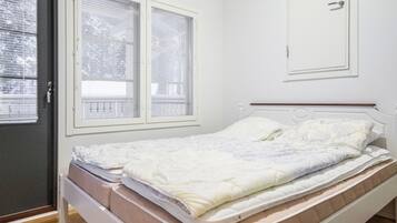 A bedroom with a bed, a wardrobe, and a door with windows.