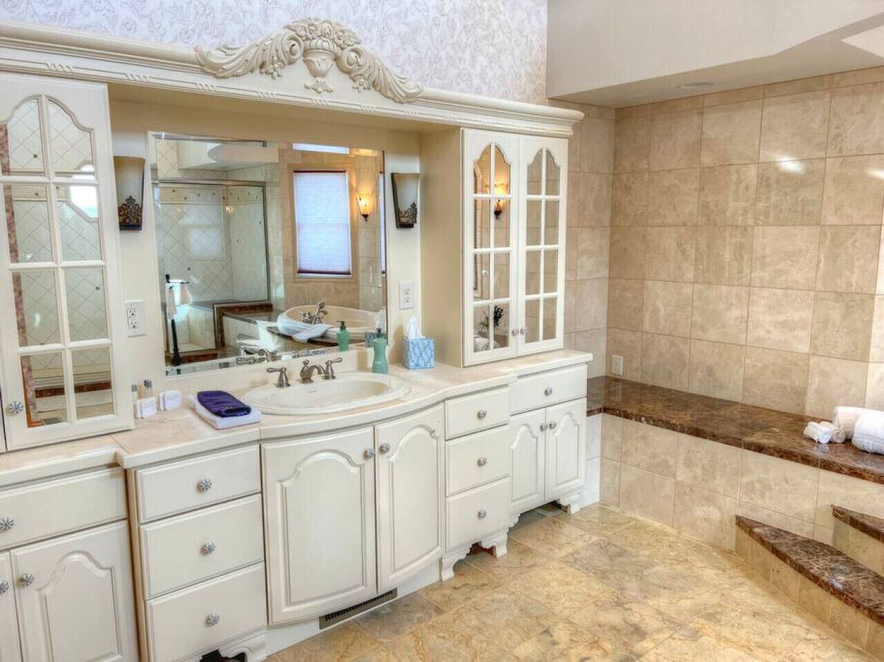 Une salle de bain spacieuse avec un grand meuble-lavabo, une douche et un sol en marbre.