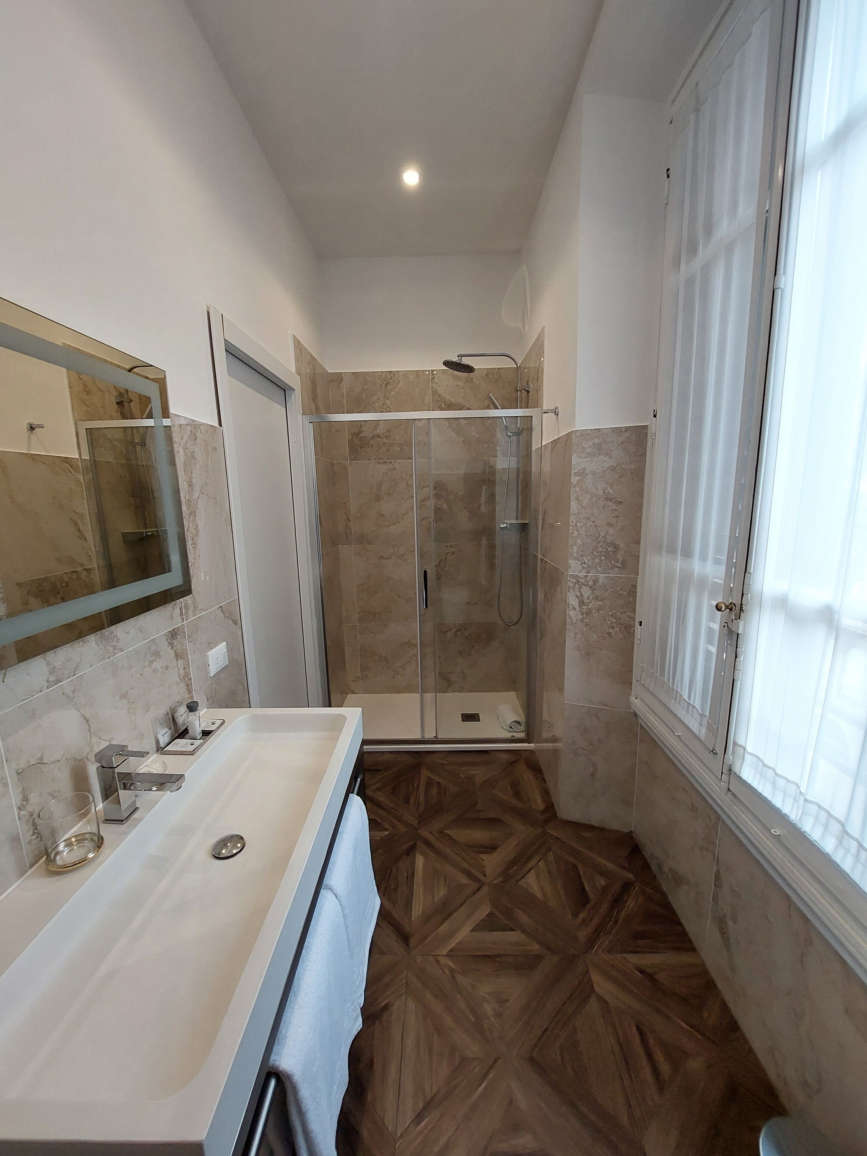 A modern bathroom with a glass shower enclosure, a large mirror, and a vanity with a sink.