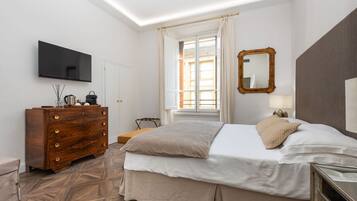 Una habitación de hotel con una cama, un aparador, un televisor, una ventana con cortinas y un espejo.