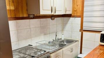 Una cocina con armarios de madera, un lavamanos de acero inoxidable y una estufa a gas.