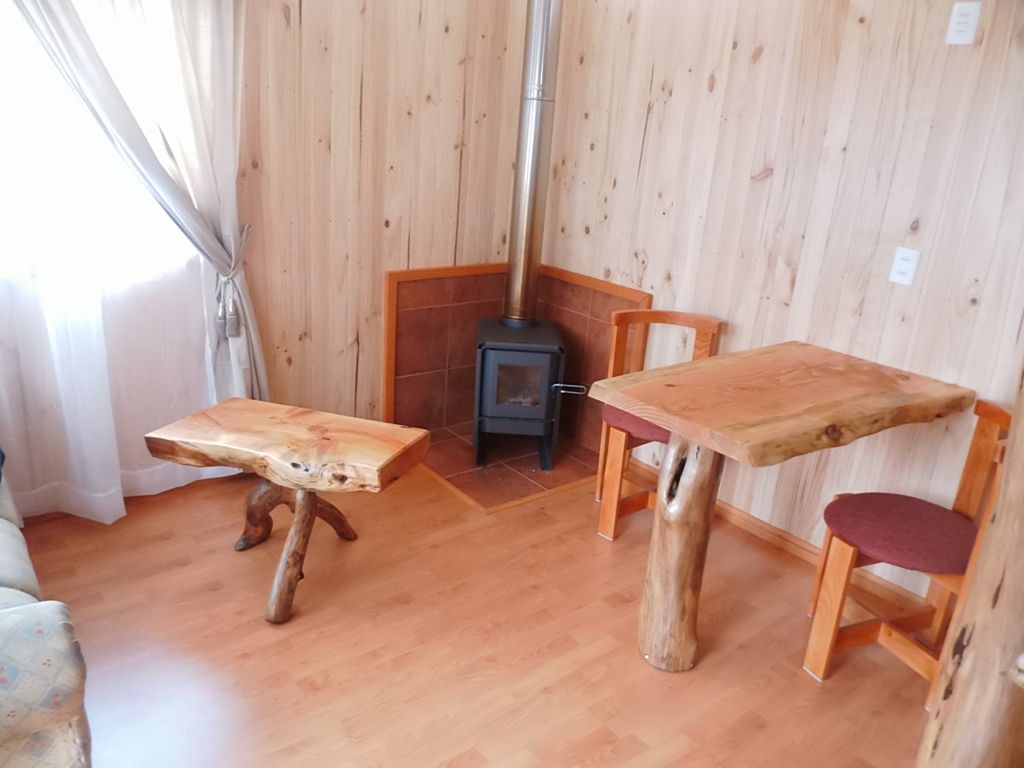 Una habitación con suelo de madera, una mesa de diseño único, una silla y un estufa de leña.
